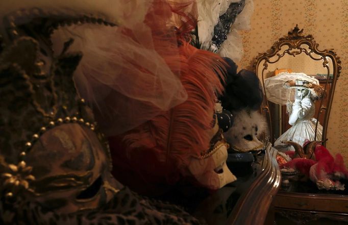 Nadia, wife of Marco Dilauro, is reflected in a mirror as she wears one of his creations, an elaborate costume for the Venice Carnival January 25, 2013. Marco Dilauro, 43, is a tax collector by day, but his real passion is making masks and costumes for the carnival. A resident of Como, northern Italy, he chooses fabrics, ribbons, lace and costume jewellery to make the period costumes after doing extensive research, and wears them at Carnival, which ends on the day before Ash Wednesday. Picture taken January 25, 2013. REUTERS/Alessandro Bianchi (ITALY - Tags: SOCIETY) Published: Led. 27, 2013, 11:51 odp.