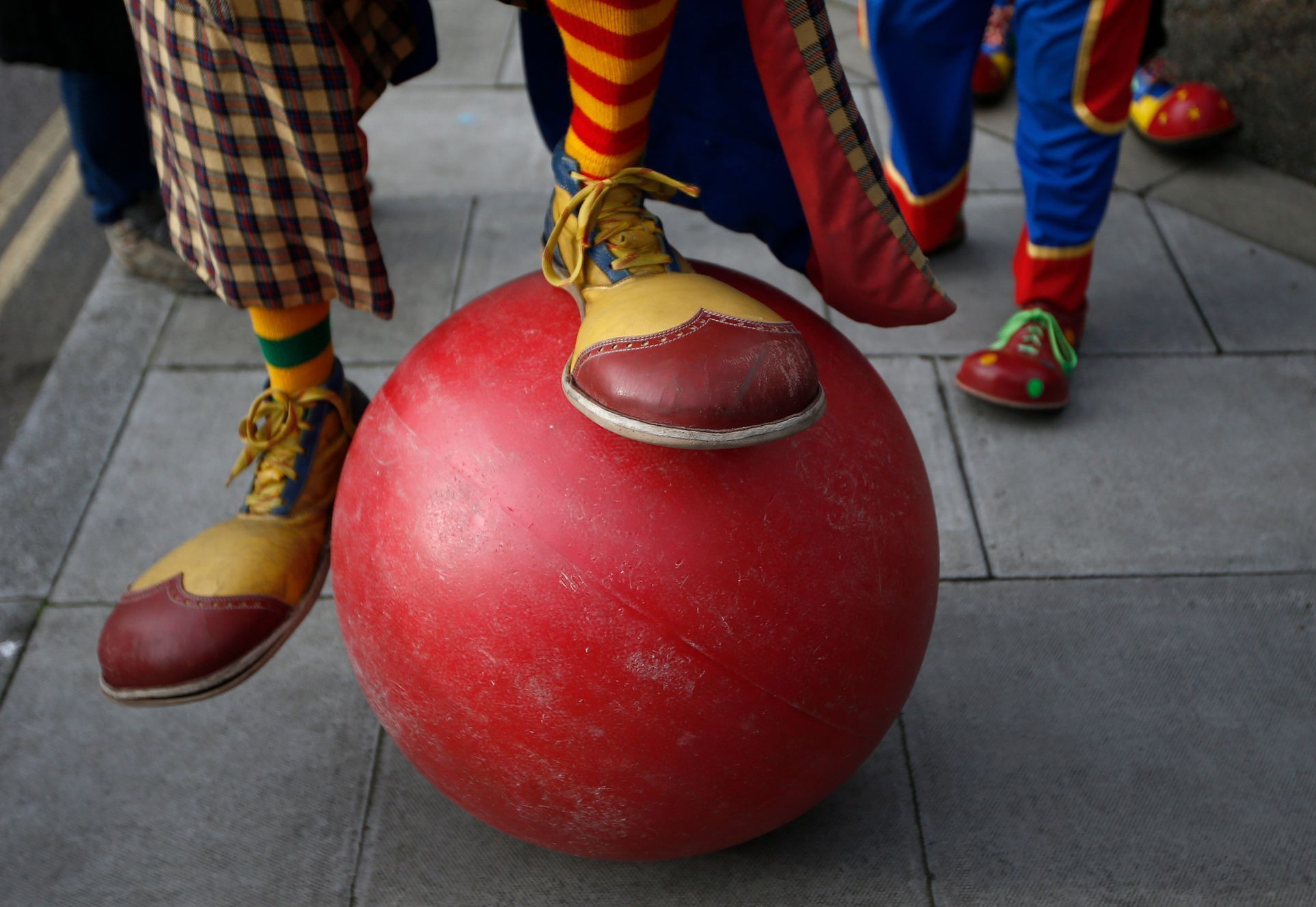A clown attempts to balance on a large ball outside the All Saints Church before the Grimaldi clown service in Dalston, north London