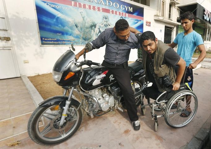 Wheelchair-bound Palestinian freelance photographer Moamen Qreiqea is helped into a wheelchair as he arrives at a gym with his brother in Gaza City October 1, 2012. Qreiqea, 25, lost both his legs in an Israeli air strike in 2008 while taking pictures east of Gaza. The father of two is determined to continue his career despite his disability. REUTERS/Suhaib Salem (GAZA - Tags: MEDIA SOCIETY) Published: Říj. 1, 2012, 3:39 odp.