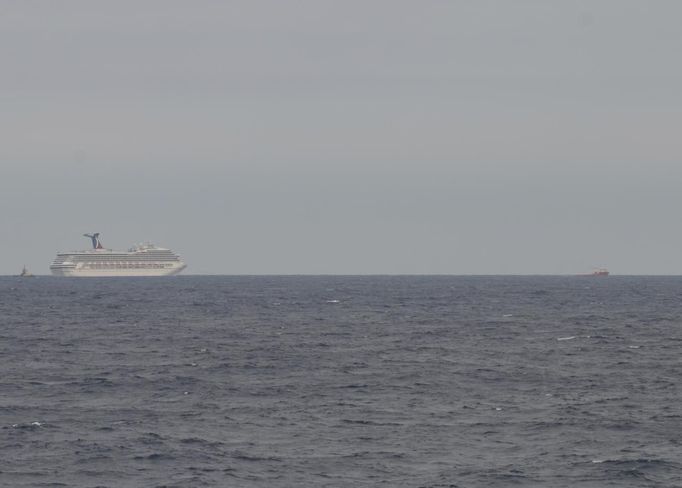 The Carnival Cruise Ship Triumph is towed by the tug vessels Pioneer and Roland Falgout in the Gulf of Mexico toward Mobile, Alabama in this February 13, 2013 Coast Guard handout photo obtained by Reuters February 14, 2013. The Triumph reported lost power due to an electical fire in the engine room, February 10, leaving more than 4,220 people enduring unsanitary conditions and food shortages. REUTERS/U.S. Coast Guard/Lt. Cmdr. Paul McConnell/Handout (UNITED STATES - Tags: TRANSPORT MARITIME BUSINESS TRAVEL) THIS IMAGE HAS BEEN SUPPLIED BY A THIRD PARTY. IT IS DISTRIBUTED, EXACTLY AS RECEIVED BY REUTERS, AS A SERVICE TO CLIENTS. FOR EDITORIAL USE ONLY. NOT FOR SALE FOR MARKETING OR ADVERTISING CAMPAIGNS Published: Úno. 14, 2013, 4:32 odp.