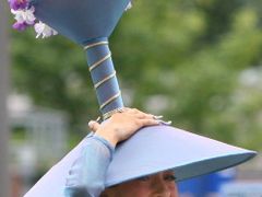 Žena s tradičním kloboukem přichází na slavný dostihový mítink Royal Ascot.
