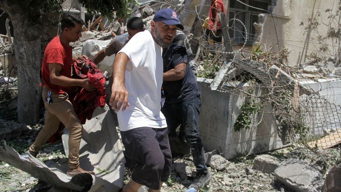 Palestinci nesou oběť izraelského úderu před sídlem agentury OSN UNRWA.