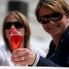 Spectators hold a drink with a strawberry on the glass at th