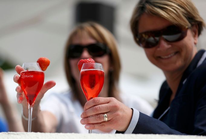 Spectators hold a drink with a strawberry on the glass at the Wimbledon Tennis Championships, in London June 26, 2013. REUTERS/Suzanne Plunkett (BRITAIN - Tags: SPORT TEN