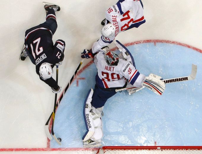 Kyle Okposo skóruje v utkání MS v hokeji 2012 USA - Francie, bráněn Kevinem Hecquefeuillem a Christobalem Huetem.