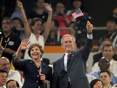 Prezident G.W.Bush s manželkou Laurou mávají z tribuny americkým sportovcům pochodujícím po ploše Národního stadionu.