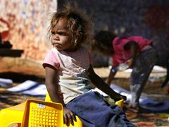 Dítě sedí vedle komunitního centra v "Hidden Valley" nedaleko australského města Alice Springs.