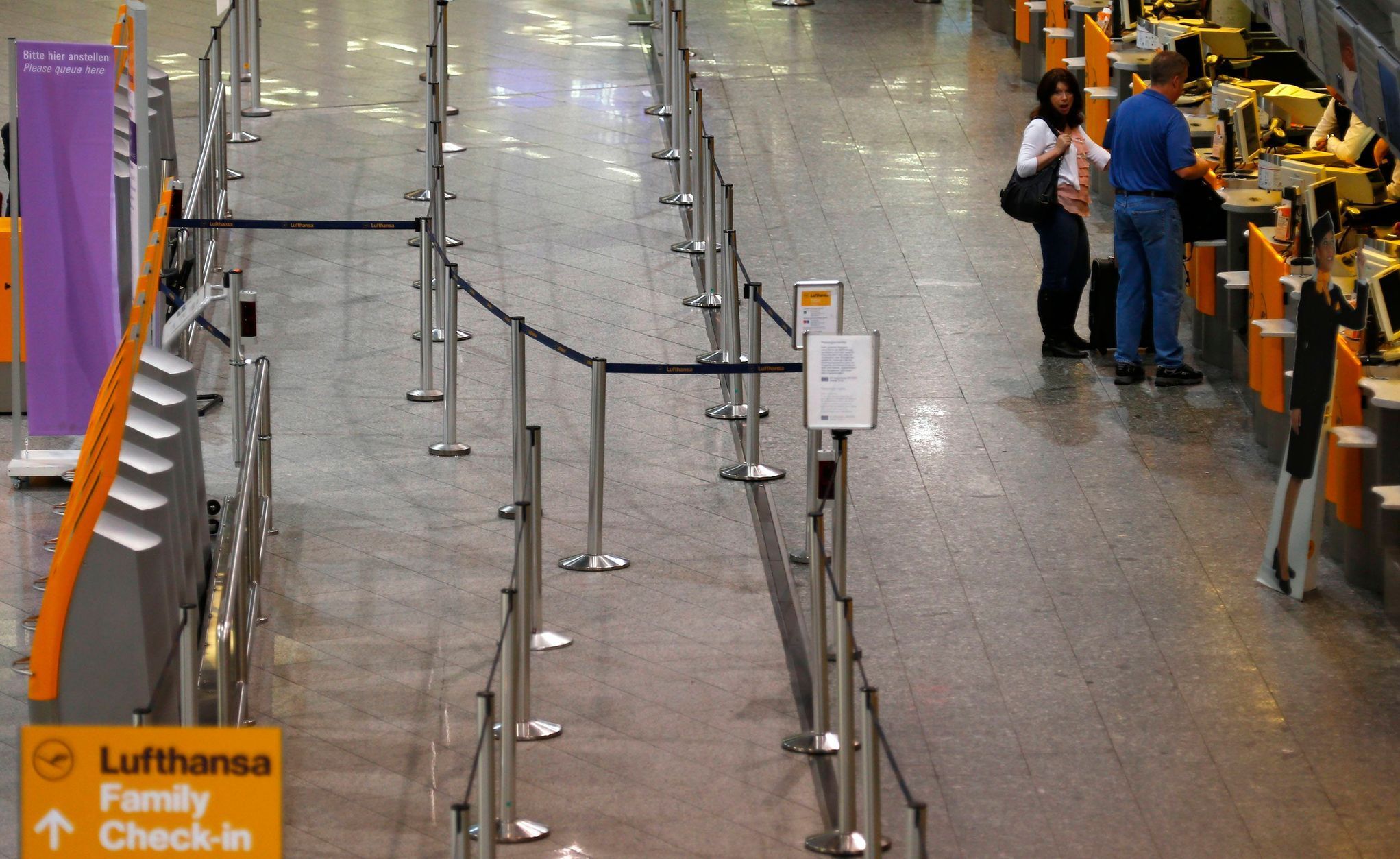 Two passengers stand at the check-in counters of German air carrier Lufthansa at Fraport airport in Frankfurt