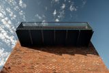 "Černý ocelový balkon rozšiřuje plochu malého bytu a zpřístupňuje střechu po původním ocelovém žebříku. Černou barvou jsou odlišeny všechny nové ocelové konstrukce v domě," popisují architekti.