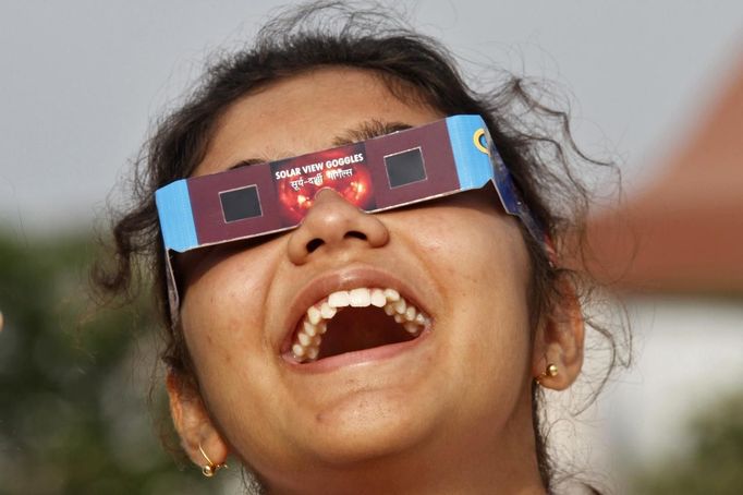 A girl reacts as she uses a pair of eclipse glasses to watch Venus passing the sun in Kolkata June 6, 2012. The planet Venus made a slow transit across the face of the sun on Tuesday, the last such passing that will be visible from Earth for 105 years. REUTERS/Rupak De Chowdhuri (INDIA - Tags: SCIENCE TECHNOLOGY) Published: Čer. 6, 2012, 8:32 dop.