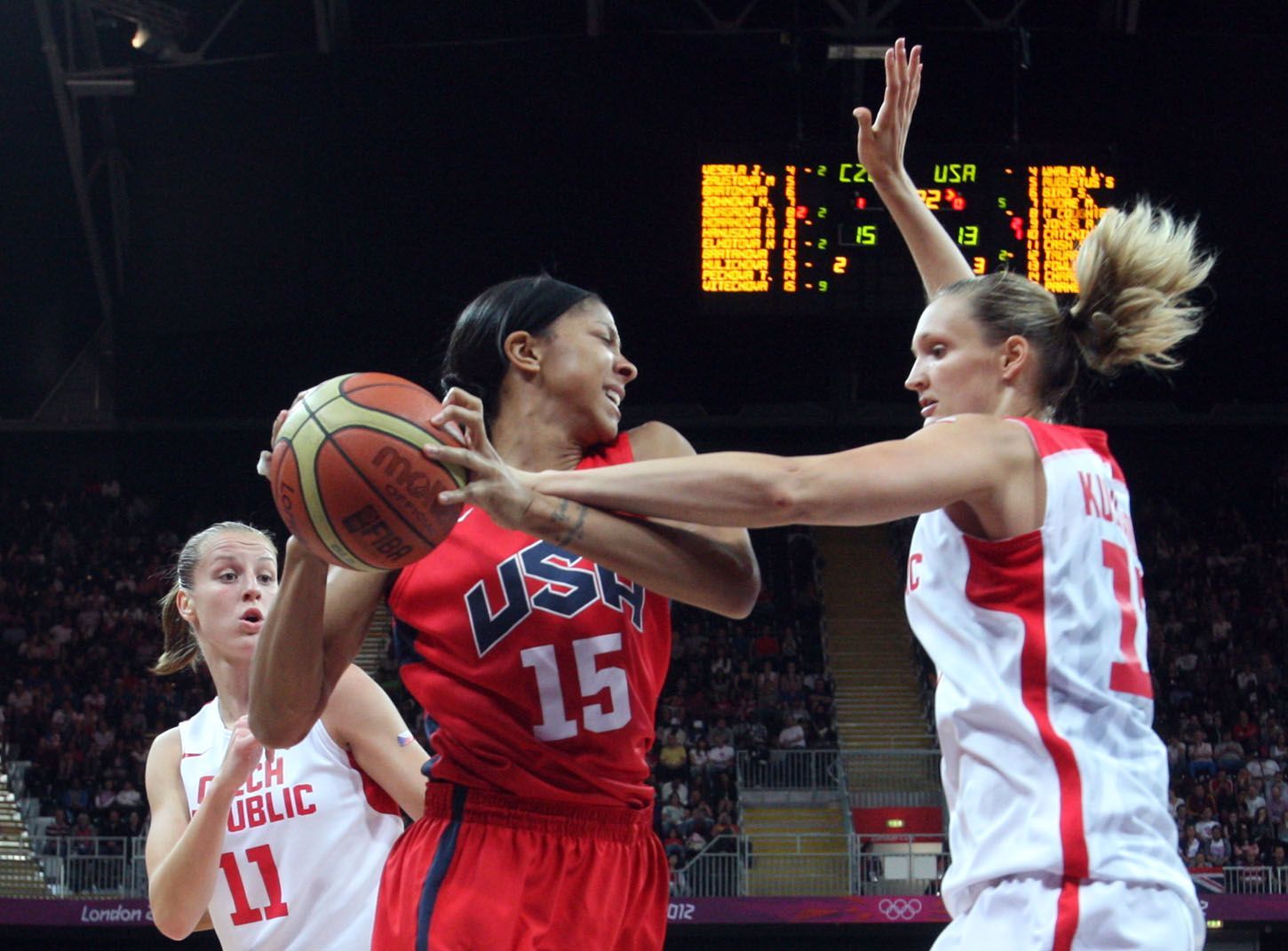 České basketbalistky Petra Kulichová (vpravo) a Kateřina Elhotová brání Američanku Candace Parkerovou v utkání skupiny A na OH 2012 v Londýně.