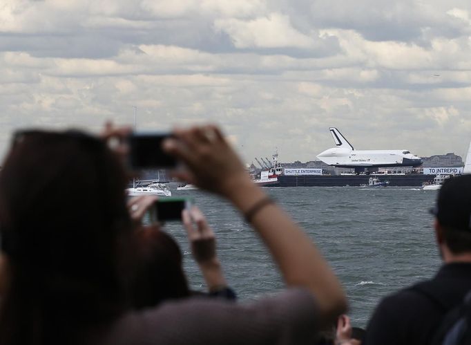 The Space Shuttle Enterprise, passes the Statue of Liberty as it rides on a barge in New York harbor, June 6, 2012. The Space Shuttle Enterprise was being moved up the Hudson River to be placed at the Intrepid Sea, Air and Space Museum. REUTERS/Brendan McDermid (UNITED STATES - Tags: SCIENCE TECHNOLOGY TRANSPORT) Published: Čer. 6, 2012, 5:22 odp.