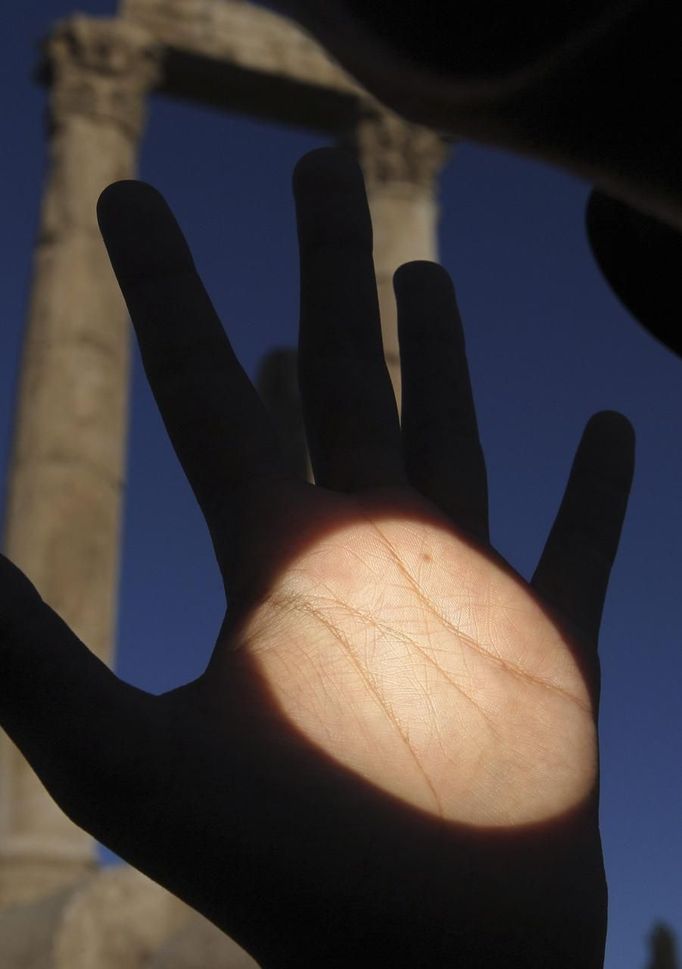 The planet Venus is seen as a black dot on a man's hand as it makes its transit across the sun, in Amman June 6, 2012. Venus made a slow transit across the face of the sun on Tuesday, the last such passing that will be visible from Earth for 105 years. REUTERS/Ali Jarekji (JORDAN - Tags: ENVIRONMENT TPX IMAGES OF THE DAY) Published: Čer. 6, 2012, 6:44 dop.