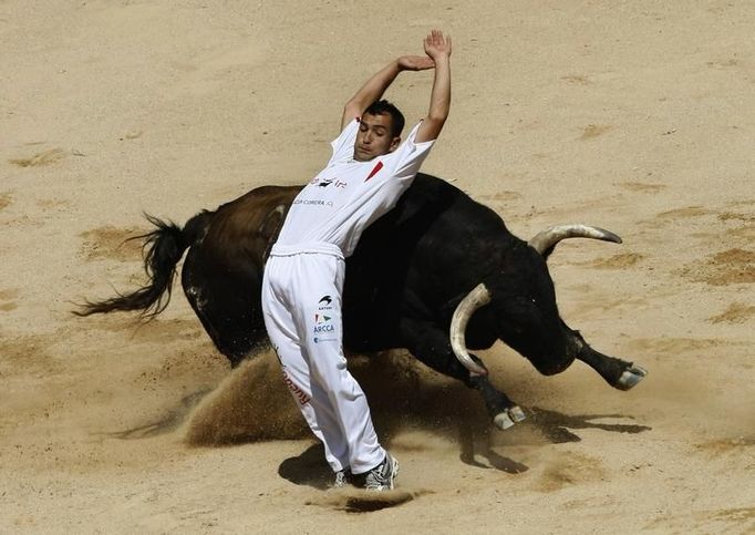 Recortador provádějící úhybný manévr během soutěže v pamplonské býčí aréně třetí den konání festival San Fermin. 8. července 2012.