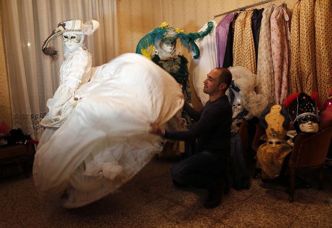 Marco Dilauro prepares as his wife Nadia wears one of his creations, an elaborate costume for the Venice Carnival January 25, 2013. Dilauro, 43, is a tax collector by day, but his real passion is making masks and costumes for the carnival. A resident of Como, northern Italy, he chooses fabrics, ribbons, lace and costume jewellery to make the period costumes after doing extensive research, and wears them at Carnival, which ends on the day before Ash Wednesday. Picture taken January 25, 2013. REUTERS/Alessandro Bianchi (ITALY - Tags: SOCIETY) Published: Led. 27, 2013, 11:32 odp.