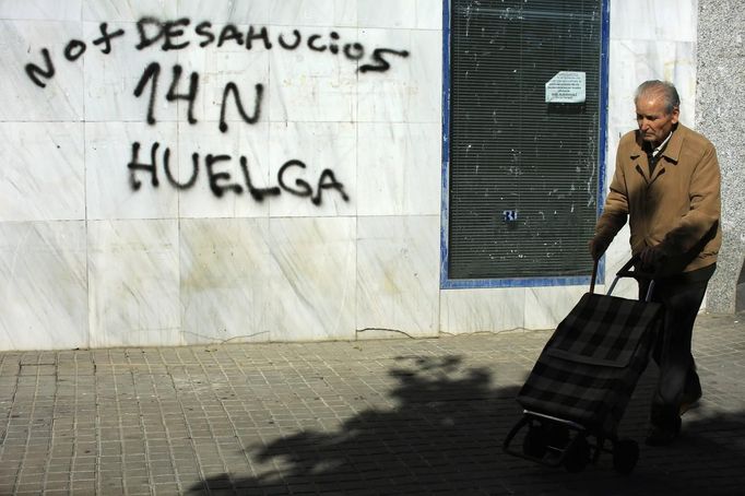 A man walks past a graffiti calling for a general strike in the Andalusian capital of Seville November 13, 2012. Spain's two largest labour unions have called for a general strike on November 14, the second against the conservative government since they took power in December and coinciding with industrial action in Portugal on the same day. The graffiti reads, "No more evictions - November 14 strike." REUTERS/Marcelo del Pozo (SPAIN - Tags: BUSINESS EMPLOYMENT POLITICS CIVIL UNREST) Published: Lis. 13, 2012, 2:49 odp.