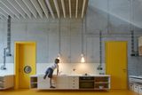 Stěžejní část v interiéru má industriální charakter. Holé betonové zdi s odhalenou elektroinstalací oživují prvky ve žluté barvě, jako jsou dveře a podlaha.