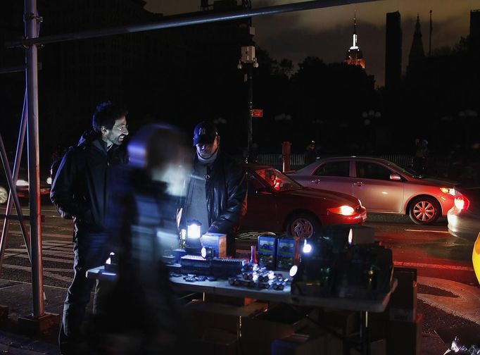 A man sells flashlights in the aftermath of Hurricane Sandy in New York October 31, 2012. New York City and the sodden U.S. Northeast began an arduous journey back to normal on Wednesday after mammoth storm Sandy killed at least 64 people in a rampage that swamped coastal cities and cut power to millions. Seen in the background is the Empire state building, one of the few buildings in the area with power. REUTERS/Carlo Allegri (UNITED STATES - Tags: SOCIETY ENVIRONMENT DISASTER) Published: Lis. 1, 2012, 4 dop.