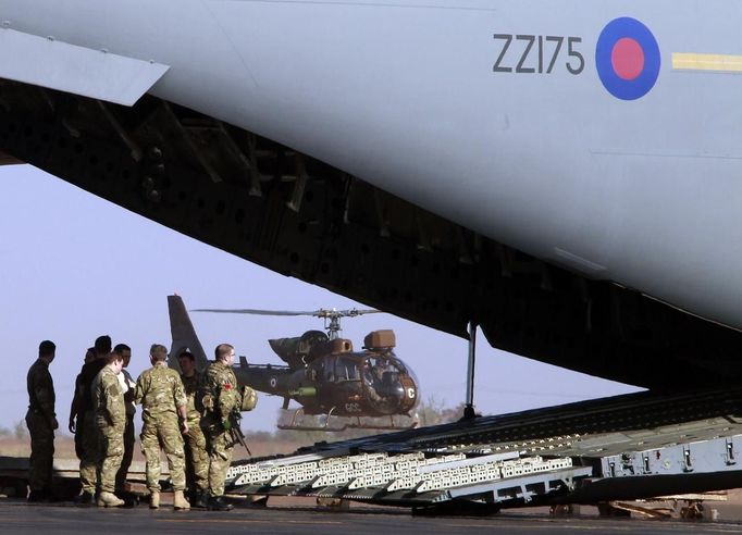 British soldiers unload a British C17 cargo aircraft while a French Gazelle helicopter takes off at the Mali air force base near Bamako January 18, 2013. The British Royal Air Force is lending logistical support to France as it sends forces to Mali. REUTERS/Eric Gaillard (MALI - Tags: CIVIL UNREST CONFLICT MILITARY) Published: Led. 18, 2013, 6:28 odp.