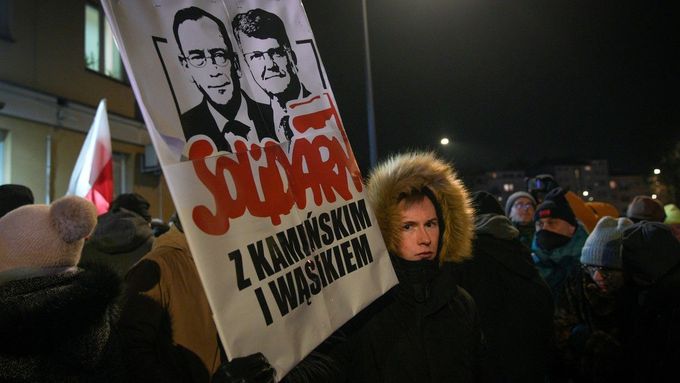 Protestující drží ceduli s podobiznami zadržených bývalých poslanců Mariusze Kaminského a Macieje Wasika poblíž policejní stanice Grochow ve Varšavě v Polsku (9. 1. 2023)