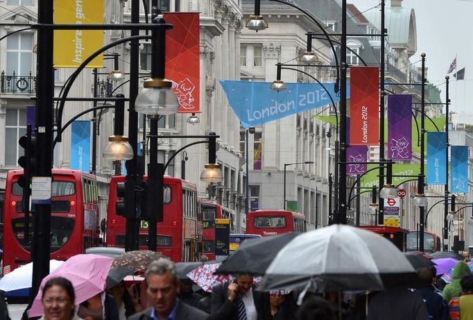 Shoppers hold umbrellas as they walk under London Olympic 2012 banners in Oxford Street in central London July 18, 2012. REUTERS/Toby Melville (BRITAIN - Tags: ENVIRONMENT SOCIETY SPORT OLYMPICS) Published: Čec. 18, 2012, 1:08 odp.