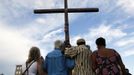 People hold a cross during a vigil for victims behind the theater where a gunman opened fire on moviegoers in Aurora, Colorado July 22, 2012. Residents of a Denver suburb mourned their dead on Sunday from a shooting rampage by a "demonic" gunman who killed 12 people and wounded 58 after opening fire at a cinema showing the new Batman movie. REUTERS/Shannon Stapleton (UNITED STATES - Tags: CRIME LAW) Published: Čec. 23, 2012, 2:29 dop.