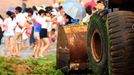 Tourists play on the beach covered by the seaweed in Qingdao in east China's Shandong province Friday July 5, 2013. Thousands of workers are cleaning the beach contaminated by the algae called enteromorpha prolifera each day as the algae blooms in the sea south to the city.