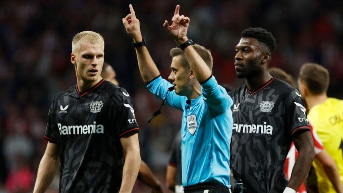 Rozhodčí Clement Turpin nařizuje k nevoli fotbalistů Leverkusenu penaltu ve prospěch Atlétika Madrid, i když chvíli předtím už odpískal konec utkání