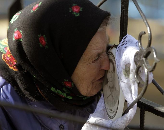 Belarussian woman kisses portrait at her relative's grave during "Radunitsa" in abandoned village of Lomysh