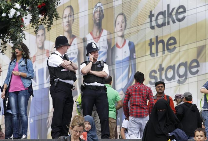 Two police officers stand on duty on the footbridge to the shopping centre adjacent to the Olympic Park in Stratford, the location of the London 2012 Olympic Games, in east London July 15, 2012. The head of private security firm G4S said on Saturday his firm only realised just over a week ago it would not be able to supply enough venue guards for this month's London Olympics, as he publicly apologised for the embarrassing failure. On Thursday, the government said it would deploy additional troops after it became clear G4S was unlikely to provide the expected 10,400 guards it was contracted to do because of problems processing applicants. REUTERS/Andrew Winning (BRITAIN - Tags: MILITARY POLITICS SOCIETY SPORT OLYMPICS) Published: Čec. 15, 2012, 2:19 odp.