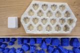 Konečnou podobu nového bonbonu pak Hájek vyryje do sádry (vlevo) a ze speciální gumy vyrobí první matrici (vpravo), která se vylije speciální dentální sádrou a vznikají první zkušební formičky (modré dole). Z nich se vyrobí zkušební várka bonbonů, která odhalí, zda je potřeba na základní formičce něco upravit či ne.
