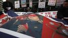 A defaced portrait of North Korea leader Kim Jong-un is seen during a rally against North Korea's nuclear test near the U.S. embassy in central Seoul February 12, 2013. North Korea conducted its third nuclear test on Tuesday in defiance of U.N. resolutions, angering the United States and Japan and prompting its only major ally, China, to call for calm. The placards read, "Crazy dog needs to be beaten down!" (R) and "Bomb North Korea's nuclear test!" (2nd R) REUTERS/Kim Hong-Ji (SOUTH KOREA - Tags: CIVIL UNREST POLITICS TPX IMAGES OF THE DAY) Published: Úno. 12, 2013, 9:13 dop.