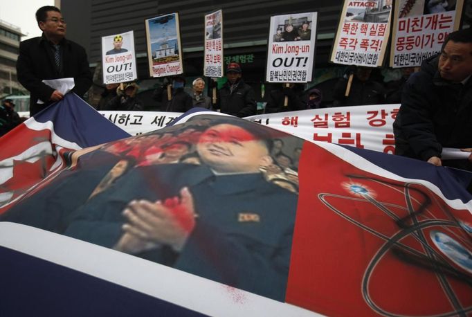 A defaced portrait of North Korea leader Kim Jong-un is seen during a rally against North Korea's nuclear test near the U.S. embassy in central Seoul February 12, 2013. North Korea conducted its third nuclear test on Tuesday in defiance of U.N. resolutions, angering the United States and Japan and prompting its only major ally, China, to call for calm. The placards read, "Crazy dog needs to be beaten down!" (R) and "Bomb North Korea's nuclear test!" (2nd R) REUTERS/Kim Hong-Ji (SOUTH KOREA - Tags: CIVIL UNREST POLITICS TPX IMAGES OF THE DAY) Published: Úno. 12, 2013, 9:13 dop.