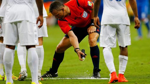 Referee Bjorn Kuipers of the Netherlands (C) marks out a line with an invisible spray during the 2014 World Cup Group D soccer match between England and Italy at the Amaz