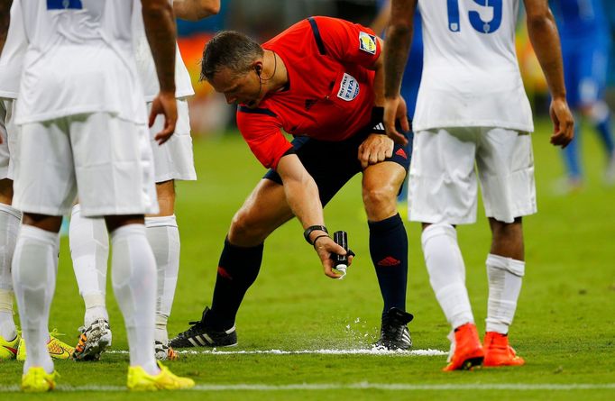 Referee Bjorn Kuipers of the Netherlands (C) marks out a line with an invisible spray during the 2014 World Cup Group D soccer match between England and Italy at the Amaz