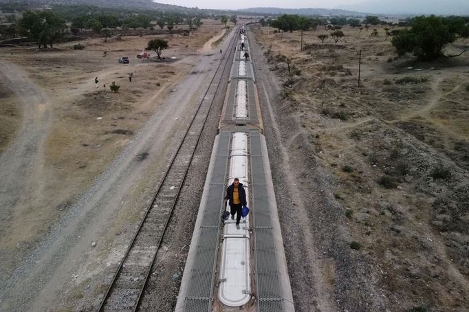Migranti, převážně z Venezuely, kráčejí na střeše železničních vagónů, když se připravují na pokračování své cesty k hranicím USA v místě známém jako El Basurero.
