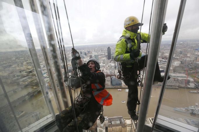 The City of London is seen behind as workers climb up the exterior of the Shard as seen from the viewing platform which opened to the public today, in London