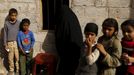 Children and a woman wait for food rations outside a charity food assistance center in Yemen's capital Sanaa