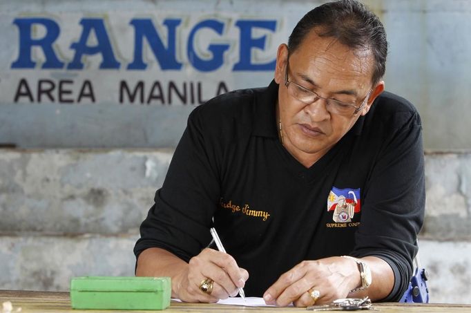 Jaime "Jimmy" Santiago, a lower court judge in Manila, takes notes before their shooting practice with fellow court judges at a police firing range in Manila March 6, 2013. Santiago, a former police officer who headed a special weapons and tactics (SWAT) unit, favours arming Filipino judges to protect themselves from disgruntled litigants who can't accept decisions and criminal syndicates whose members were sent to jail. There had been cases of shootings inside courtrooms. REUTERS/Romeo Ranoco (PHILIPPINES - Tags: POLITICS CRIME LAW) Published: Dub. 4, 2013, 10:59 dop.