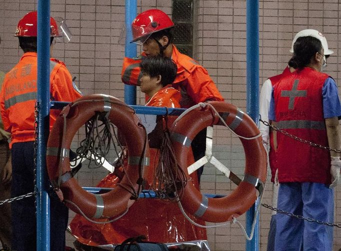 A survivor (C) is taken onto shore after being rescued from the sea in Hong Kong October 1, 2012. A ferry carrying more than 120 passengers sank south of Hong Kong late on Monday after a collision with a tug boat, a government spokeswoman said. Seventy-four people had been rescued so far off Lamma island, an area popular with tourists and expatriates, the government spokeswoman said. REUTERS/Tyrone Siu (CHINA - Tags: DISASTER MARITIME) Published: Říj. 1, 2012, 3:21 odp.