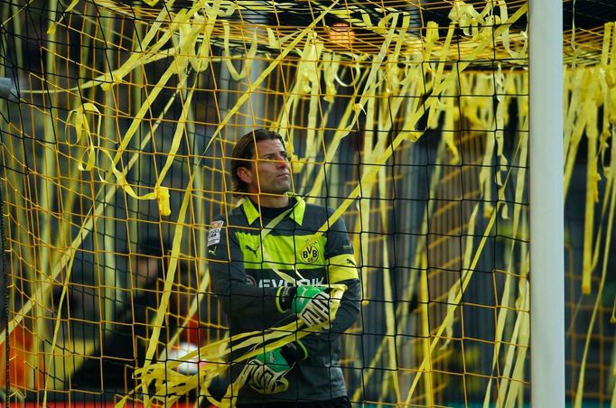 Dortmundský brankář Roman Weidenfeller uklízí před začátkem zápasu s Wolfsburgem konfety.