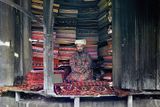 Rok 1911. Obchodník na tržišti v Samarkandu (v současnosti druhé největší město v Uzbekistánu) nabízí látky z hedvábí, bavlny a vlny a tradiční koberce. V horní části stánku visí zarámovaná strana koránu.