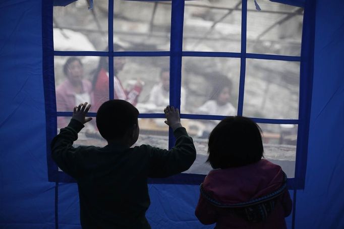 Children look out from inside a tent after Saturday's earthquake in Lingguan town of Baoxing county, Sichuan province April 22, 2013. Rescuers struggled to reach a remote, rural corner of southwestern China on Sunday as the toll of the dead and missing from the country's worst earthquake in three years climbed to 208 with almost 1,000 serious injuries. The 6.6 magnitude quake struck in Lushan county, near the city of Ya'an in the southwestern province of Sichuan, close to where a devastating 7.9 quake hit in May 2008, killing 70,000. REUTERS/Aly Song (CHINA - Tags: DISASTER ENVIRONMENT) Published: Dub. 22, 2013, 8:03 dop.