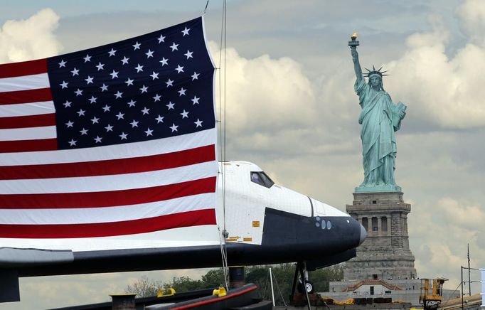 The Space Shuttle Enterprise, passes the Statue of Liberty as it rides on a barge in New York harbor, June 6, 2012. The Space Shuttle Enterprise was being moved up the Hudson River to be placed at the Intrepid Sea, Air and Space Museum. REUTERS/Mike Segar (UNITED STATES - Tags: TRANSPORT SCIENCE TECHNOLOGY) Published: Čer. 6, 2012, 5:09 odp.