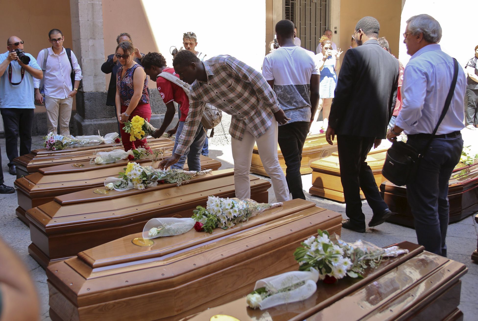 People put flowers on the coffins of 13 unidentified migrants who died in the April 19, 2015 shipwreck, during an inter-faith funeral service in Catania