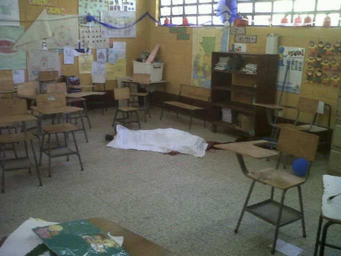 The body of a student lies in a classroom at a primary school in Tactic, in Alta Verapaz region, some 189km (117 miles) from Guatemala City, September 12, 2012. According to local media, a man entered the school and killed two children, one 8-years-old and the other 13, with a machete. The man was later lynched by a mob, who beat him up and burned him alive. REUTERS/Volunteers Firefighters/Handout (GUATEMALA - Tags: EDUCATION CRIME LAW) FOR EDITORIAL USE ONLY. NOT FOR SALE FOR MARKETING OR ADVERTISING CAMPAIGNS. THIS IMAGE HAS BEEN SUPPLIED BY A THIRD PARTY. IT IS DISTRIBUTED, EXACTLY AS RECEIVED BY REUTERS, AS A SERVICE TO CLIENTS Published: Zář. 12, 2012, 8:33 odp.