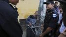 Police officers stand next on a man who is tied up and beaten by villagers, after he was accused of theft, at Tactic, in Alta Verapaz region, about 189km (117 miles) from Guatemala City, September 13, 2012. The local community tied up and beat four men who were accused of theft in the aftermath of a school killing, which had occurred on Wednesday. The man, who had entered a classroom and killed two children, ages 8 and 13, with a machete, was lynched and burnt alive by a mob, local media reported. REUTERS/Jorge Dan Lopez (GUATEMALA - Tags: CRIME LAW SOCIETY) Published: Zář. 13, 2012, 6:15 odp.