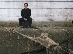 Muž sedí ve městě Sinujiu na severokorejské straně řeky Ja-lu, která odděluje Severní Koreu od Číny