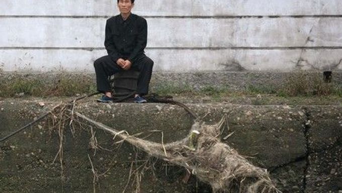 Muž sedí ve městě Sinujiu na severokorejské straně řeky Ja-lu, která odděluje Severní Koreu od Číny