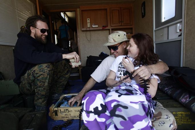 Kent Josephson, center, shares a laugh with his daughter-in-law Jesse Josephson and son Danny Josephson as he organizes his 8mm tracer rounds during the Big Sandy Shoot in Mohave County, Arizona March 23, 2013. The Big Sandy Shoot is the largest organized machine gun shoot in the United States attended by shooters from around the country. Vintage and replica style machine guns and cannons are some of the weapons displayed during the event. Picture taken March 22, 2013. REUTERS/Joshua Lott (UNITED STATES - Tags: SOCIETY) Published: Bře. 25, 2013, 3:35 odp.